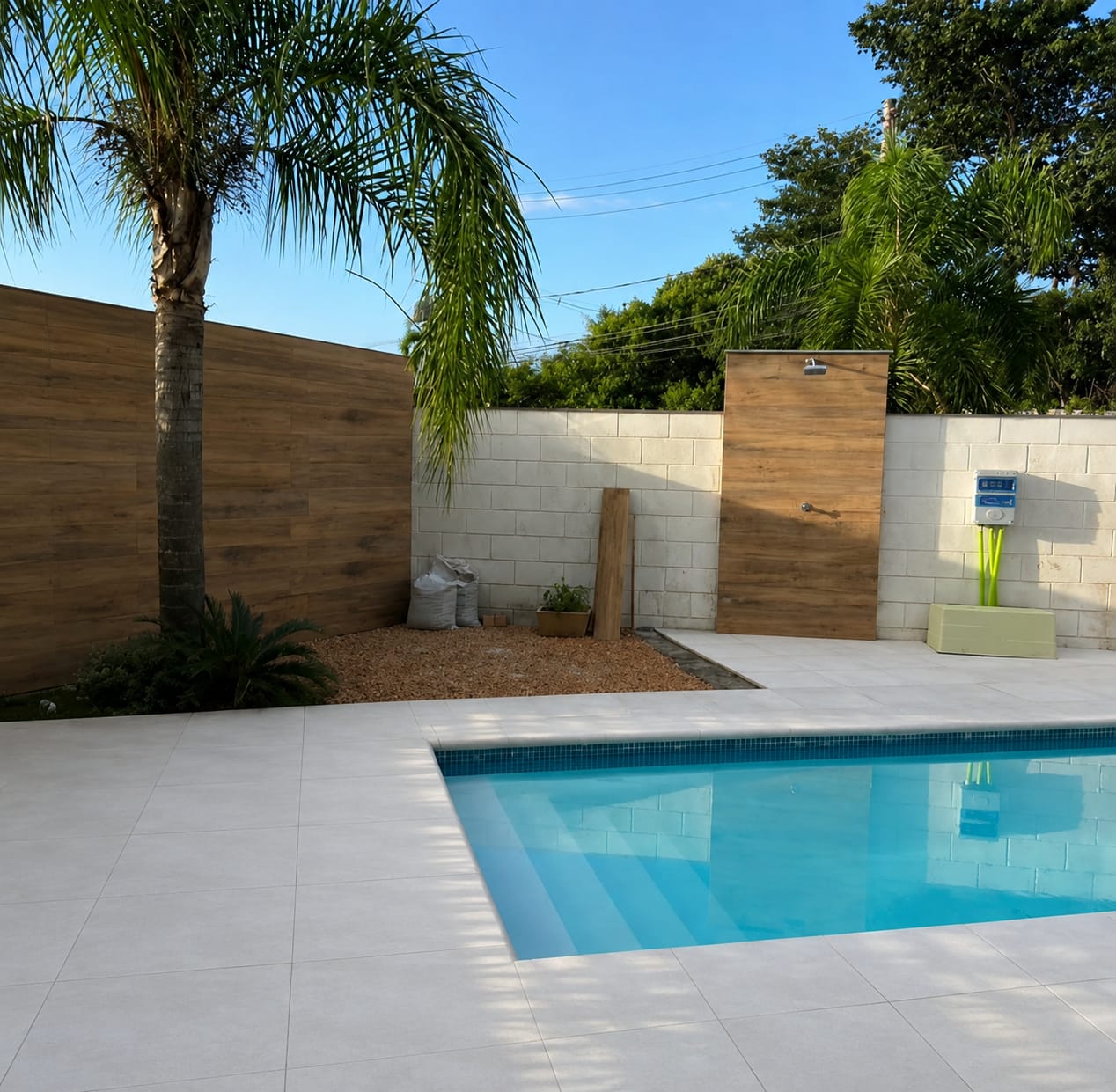 Depois: área da piscina finalizada com piso claro e parede amadeirada