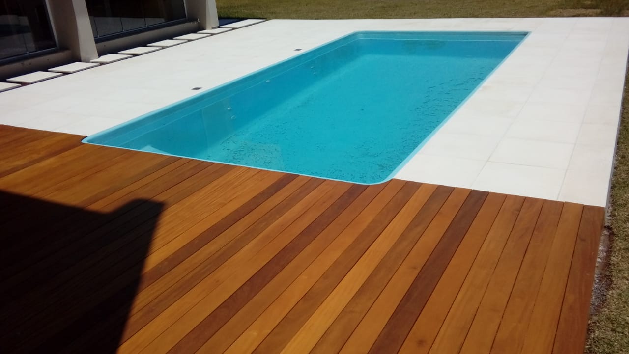 Piscina com pisos claros e deck de madeira