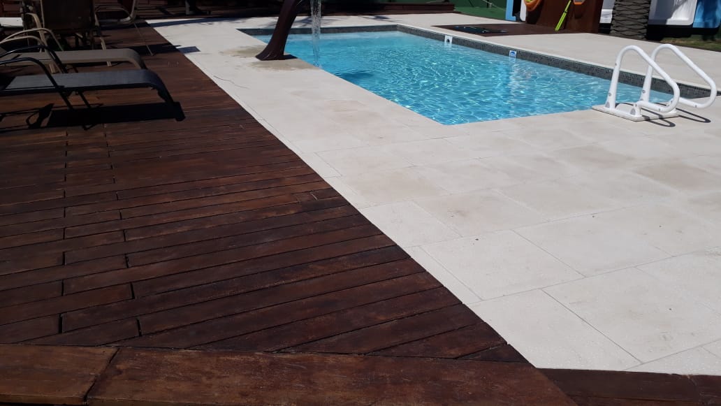 Piscina com piso atérmico claro e deck escuro