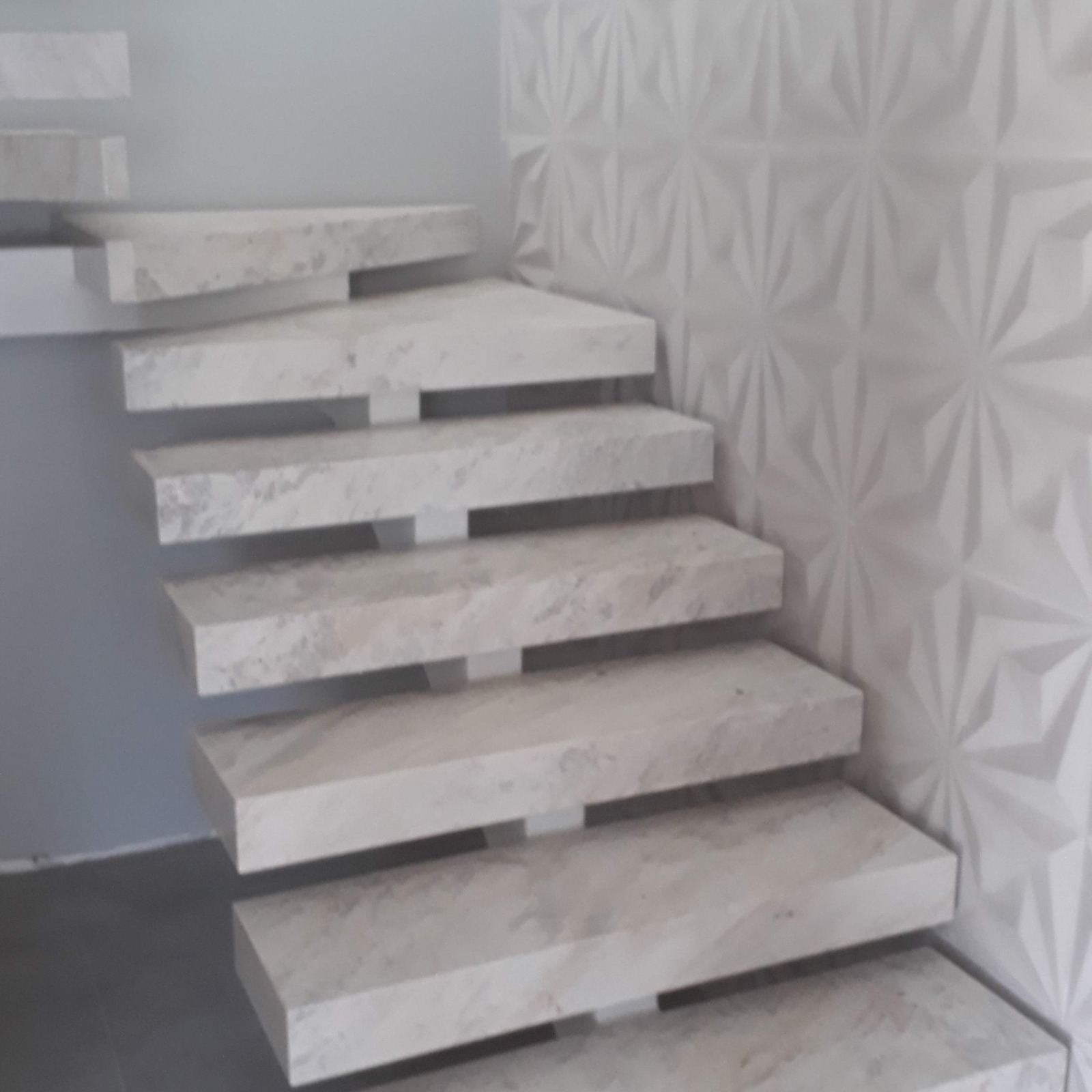 Escada em mármore claro com parede de textura geométrica