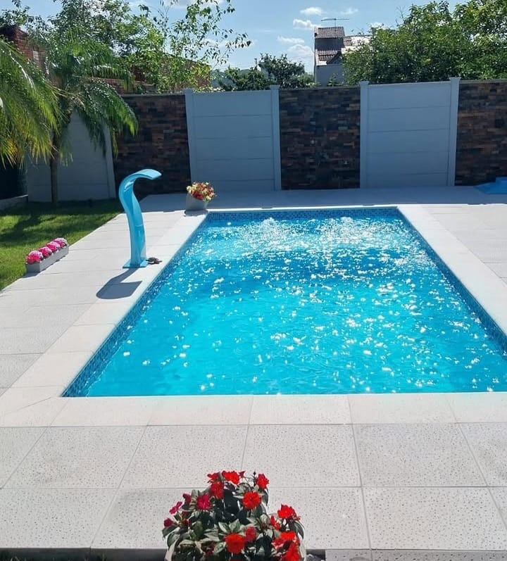 Piscina finalizada com água azul, borda clara e paisagismo