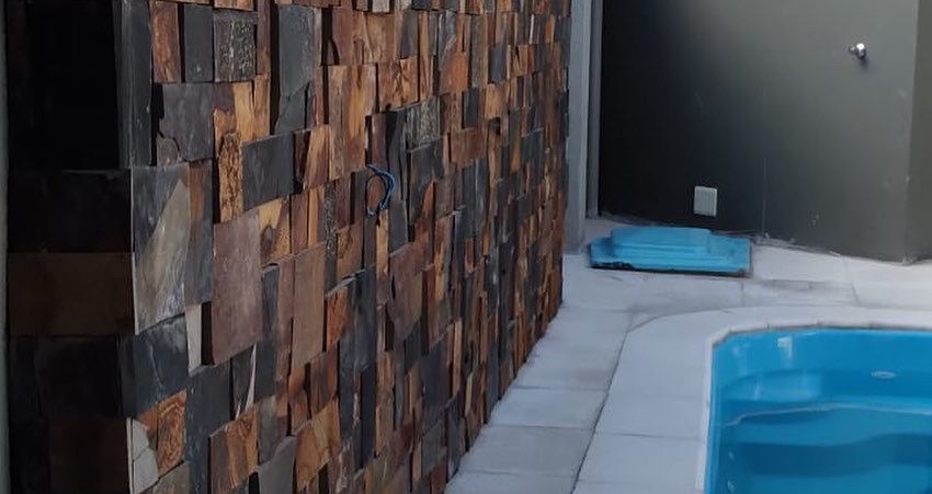 Parede de pedras naturais ao lado de piscina